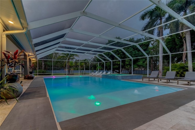 view of swimming pool featuring glass enclosure, a patio area, and an in ground hot tub