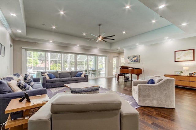 living room featuring dark hardwood / wood-style floors, a raised ceiling, and ceiling fan