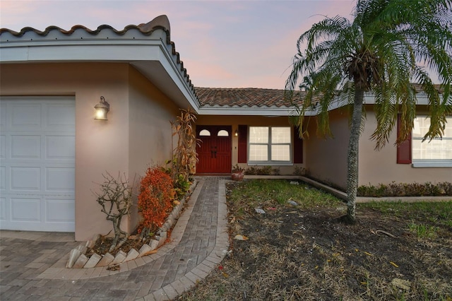 exterior entry at dusk featuring a garage