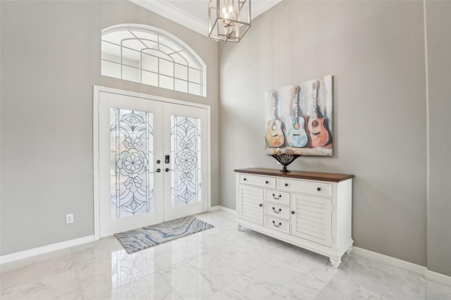 entrance foyer featuring a high ceiling, a chandelier, crown molding, and french doors