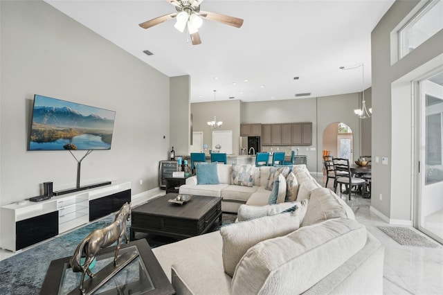 living room with a towering ceiling and ceiling fan with notable chandelier