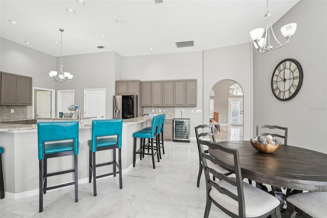 dining area with a notable chandelier, a high ceiling, and wine cooler