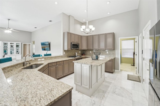 kitchen featuring a high ceiling, kitchen peninsula, sink, and stainless steel appliances