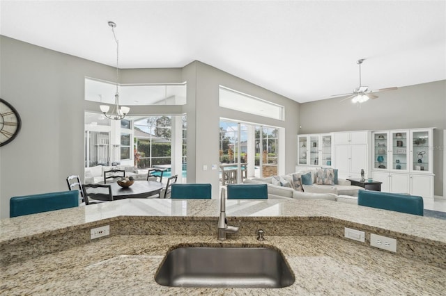 kitchen featuring light stone countertops, sink, and ceiling fan with notable chandelier