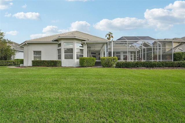 back of property with glass enclosure and a lawn