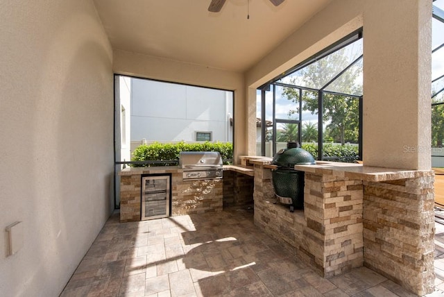 view of patio / terrace featuring grilling area, ceiling fan, exterior kitchen, and glass enclosure