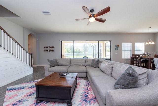 living room with a wealth of natural light, wood-type flooring, and ceiling fan with notable chandelier