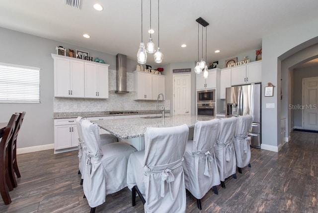 kitchen with white cabinetry, sink, stainless steel appliances, and wall chimney range hood