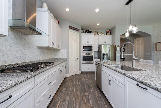 kitchen with appliances with stainless steel finishes, white cabinetry, dark wood-type flooring, and wall chimney range hood