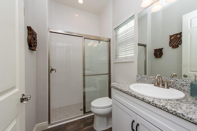 bathroom featuring toilet, vanity, a shower with door, and hardwood / wood-style flooring