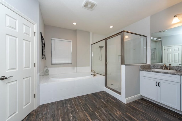 bathroom with hardwood / wood-style floors, vanity, and shower with separate bathtub