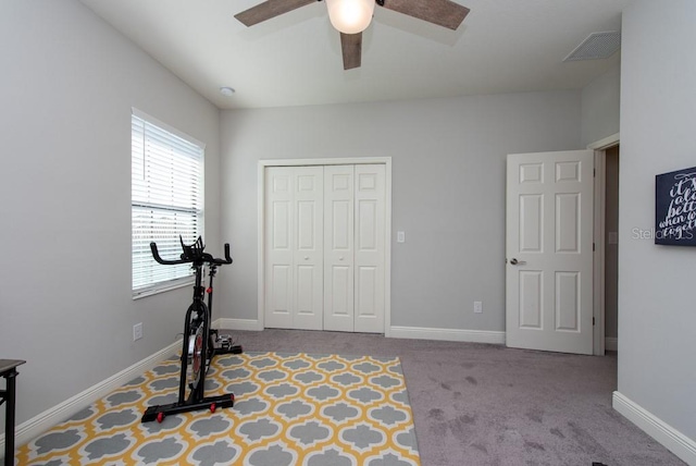 workout room with ceiling fan and light colored carpet