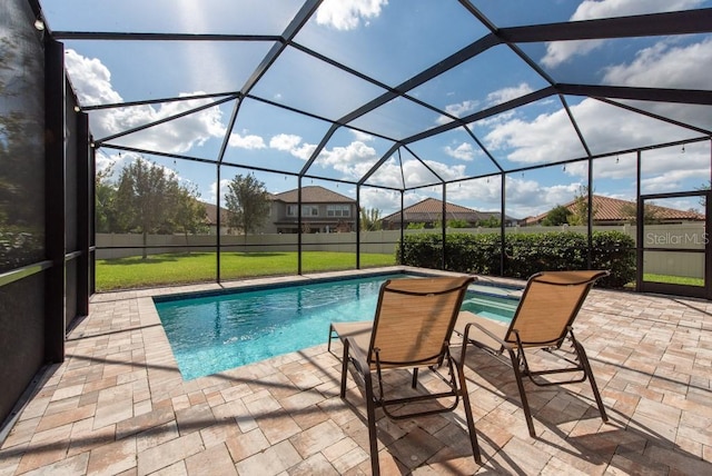 view of pool featuring a lawn, glass enclosure, and a patio area