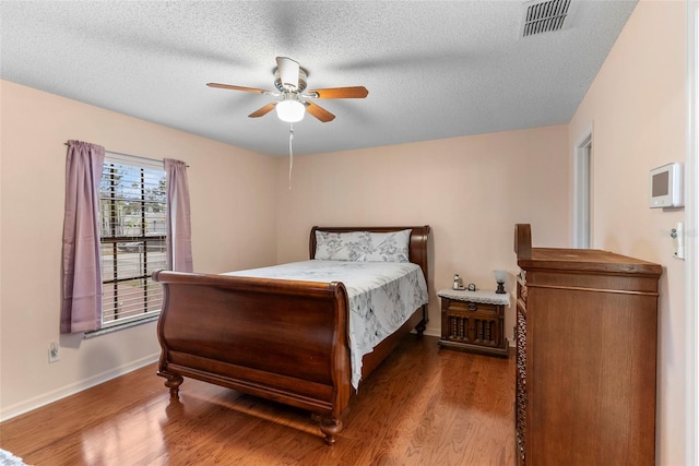 bedroom with a textured ceiling, ceiling fan, and hardwood / wood-style flooring