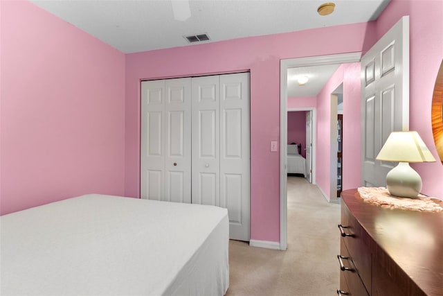 bedroom with ceiling fan, light colored carpet, and a closet