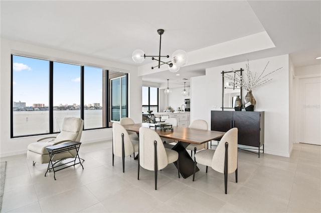 dining space featuring a notable chandelier, a healthy amount of sunlight, a water view, and light tile patterned floors