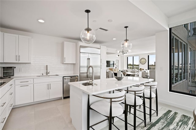 kitchen with sink, appliances with stainless steel finishes, hanging light fixtures, and white cabinetry