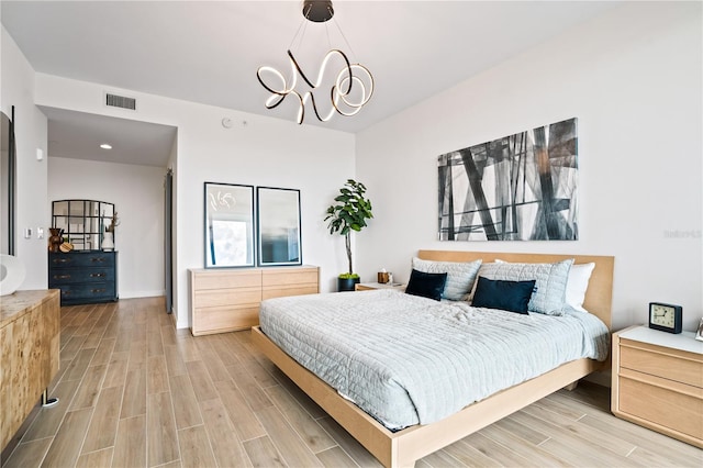 bedroom with light hardwood / wood-style flooring and a notable chandelier