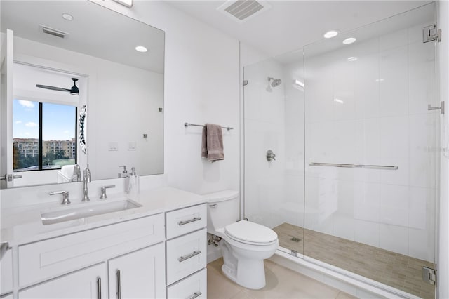 bathroom with a shower with shower door, toilet, ceiling fan, vanity, and tile patterned flooring