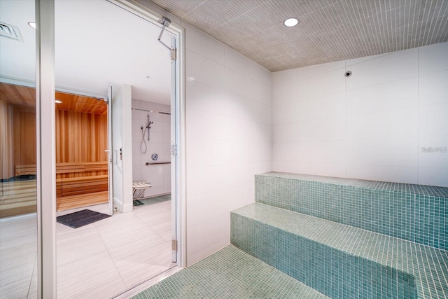 stairway featuring tile patterned floors and tile walls