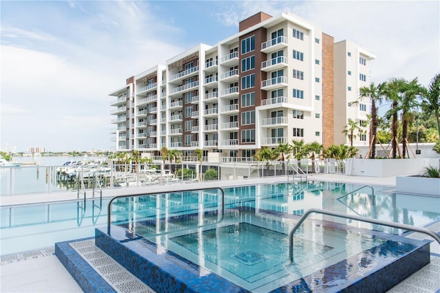 view of pool with a water view and a community hot tub