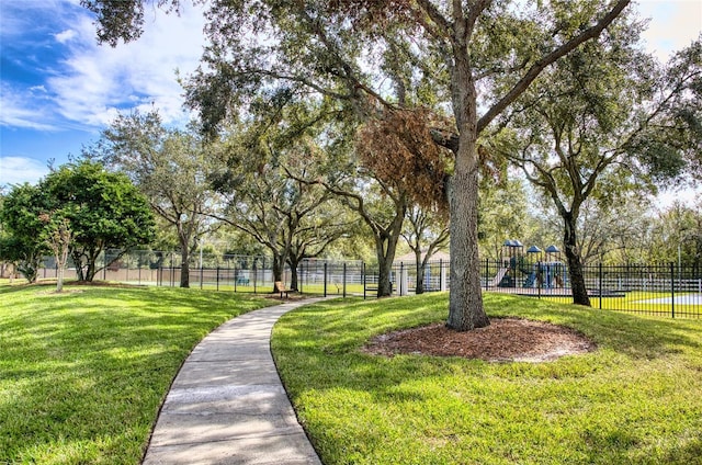 surrounding community with playground community, fence, and a lawn