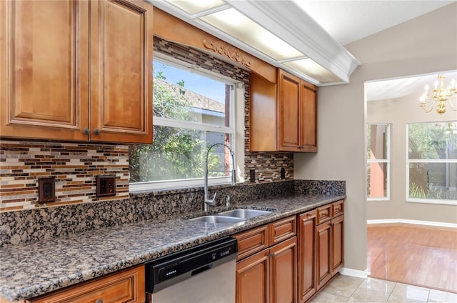 kitchen featuring dishwasher, backsplash, a sink, and brown cabinets