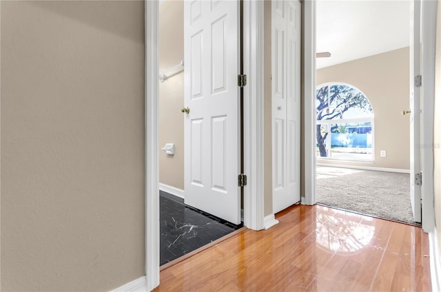 hall with baseboards and wood finished floors