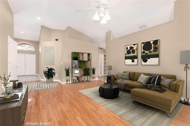 living room with light wood finished floors, baseboards, high vaulted ceiling, and ceiling fan