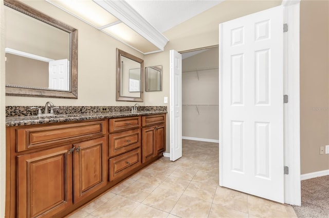 bathroom with a sink, double vanity, tile patterned flooring, and baseboards