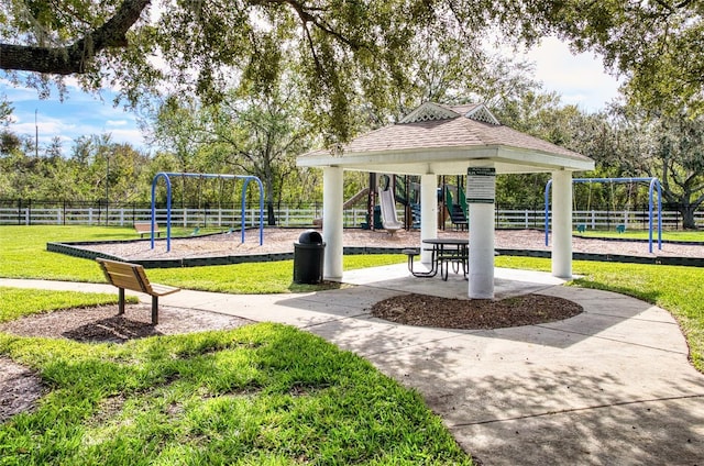 view of home's community featuring playground community, a lawn, and fence