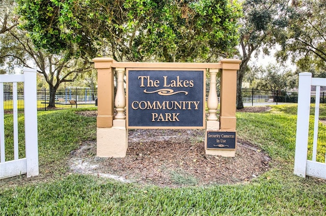 community / neighborhood sign featuring a lawn and fence