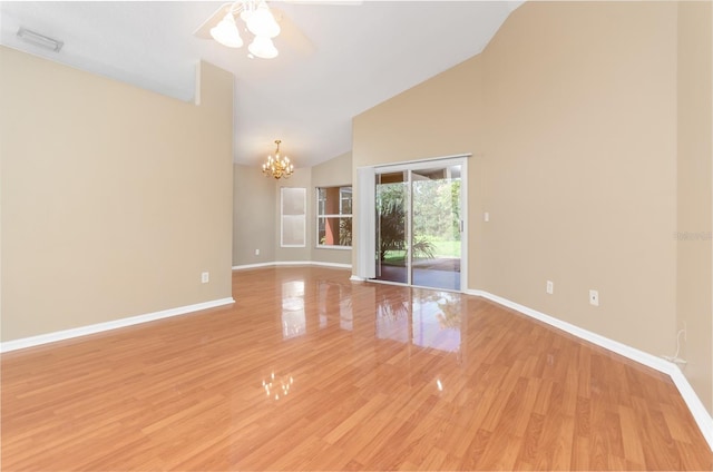 unfurnished room with light wood-style flooring, ceiling fan with notable chandelier, high vaulted ceiling, visible vents, and baseboards