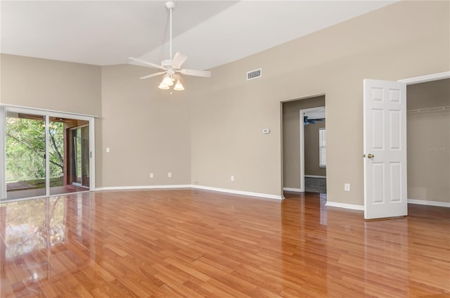 unfurnished room with light wood-style flooring, a ceiling fan, high vaulted ceiling, visible vents, and baseboards