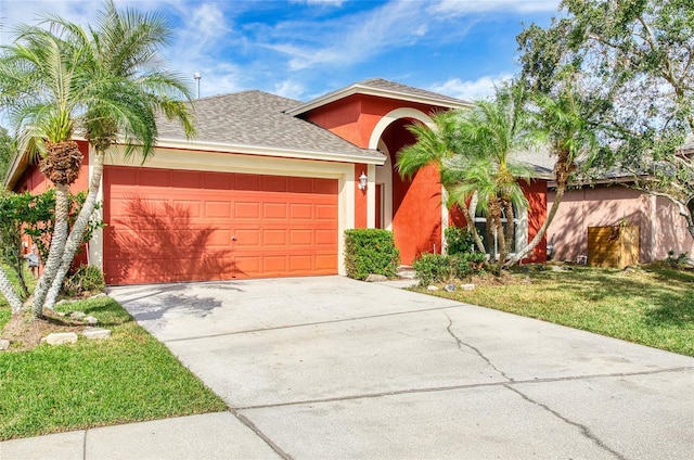 mediterranean / spanish home with roof with shingles, concrete driveway, a garage, stucco siding, and a front yard