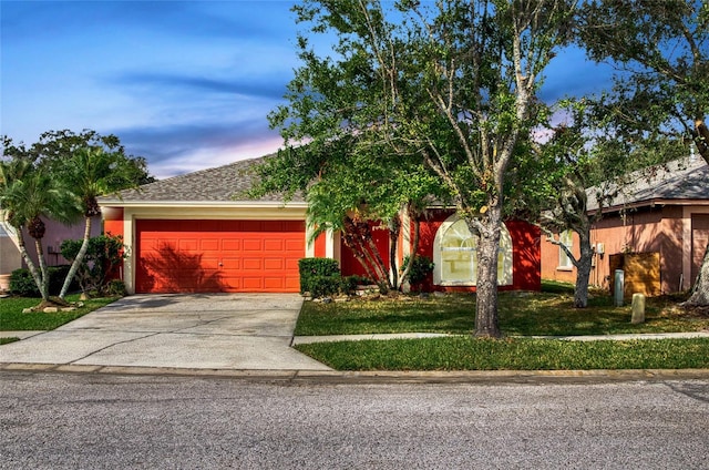 obstructed view of property featuring a front yard, an attached garage, and driveway