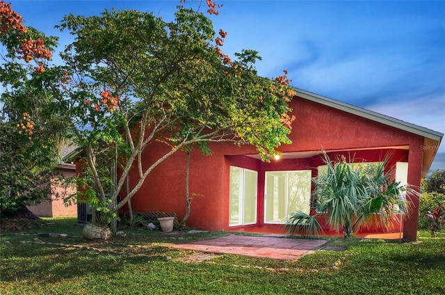 rear view of property with a yard and stucco siding