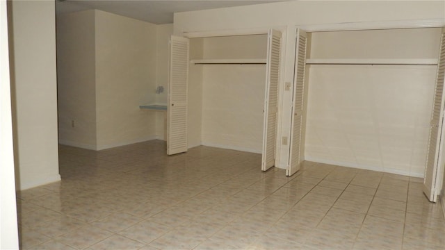 unfurnished bedroom featuring light tile patterned floors and multiple closets