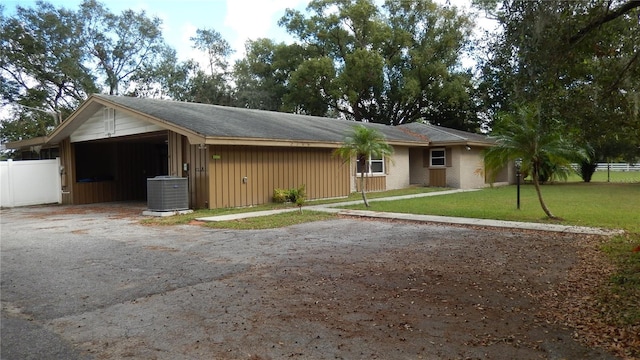 ranch-style home featuring central AC unit, a carport, and a front yard