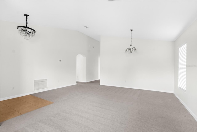 carpeted empty room featuring vaulted ceiling and a notable chandelier