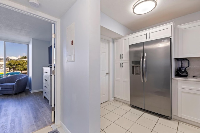 kitchen with white cabinets, stainless steel refrigerator with ice dispenser, and light wood-type flooring