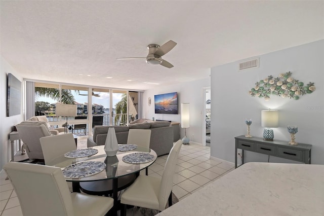 dining area with a wall of windows, light tile patterned floors, ceiling fan, and a textured ceiling