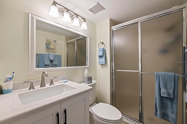 bathroom with toilet, vanity, and a shower with shower door