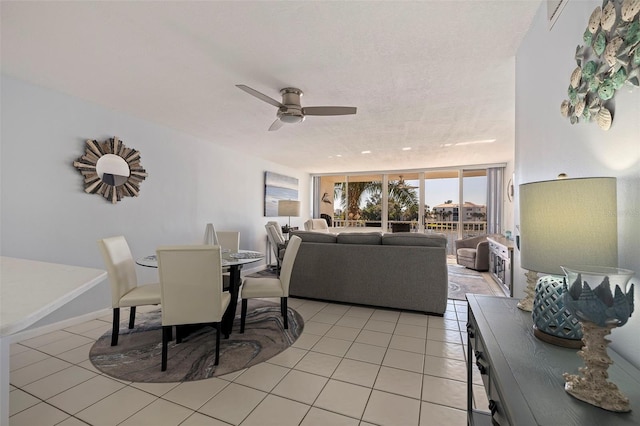 tiled dining space featuring expansive windows, ceiling fan, and a textured ceiling