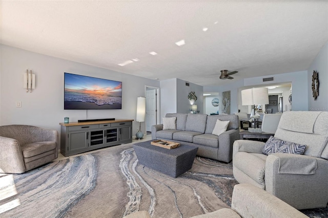 living room with ceiling fan and a textured ceiling