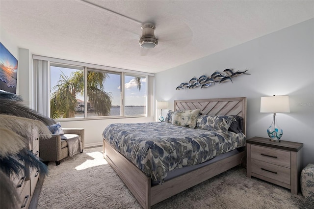 carpeted bedroom featuring a textured ceiling and ceiling fan