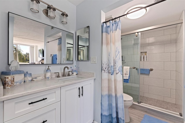 bathroom with toilet, vanity, wood-type flooring, and a tile shower