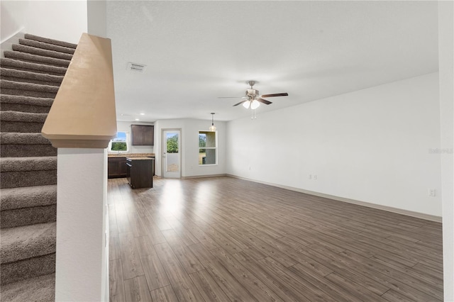 unfurnished living room with dark wood-type flooring and ceiling fan