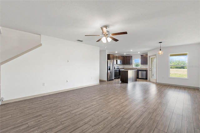 unfurnished living room with light wood-type flooring and ceiling fan