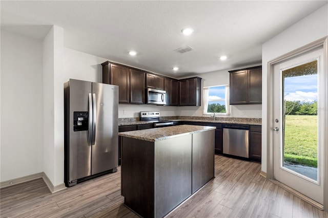 kitchen featuring dark brown cabinetry, light wood-type flooring, appliances with stainless steel finishes, and a kitchen island